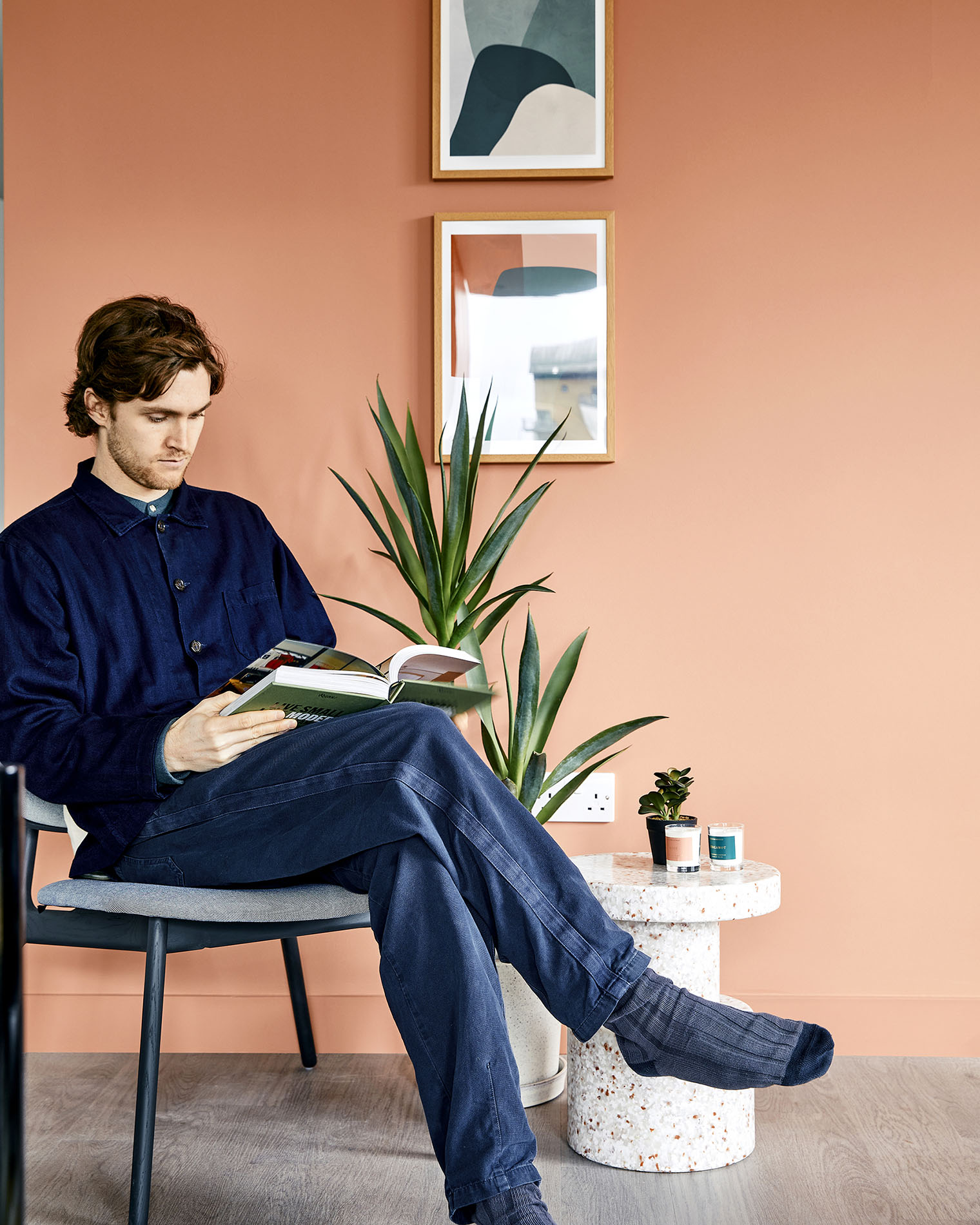 Man sitting reading by plant